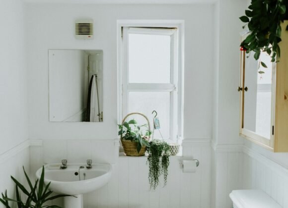 Organized small apartment bathroom with over-toilet shelf and wicker baskets