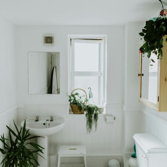 Organized small apartment bathroom with over-toilet shelf and wicker baskets