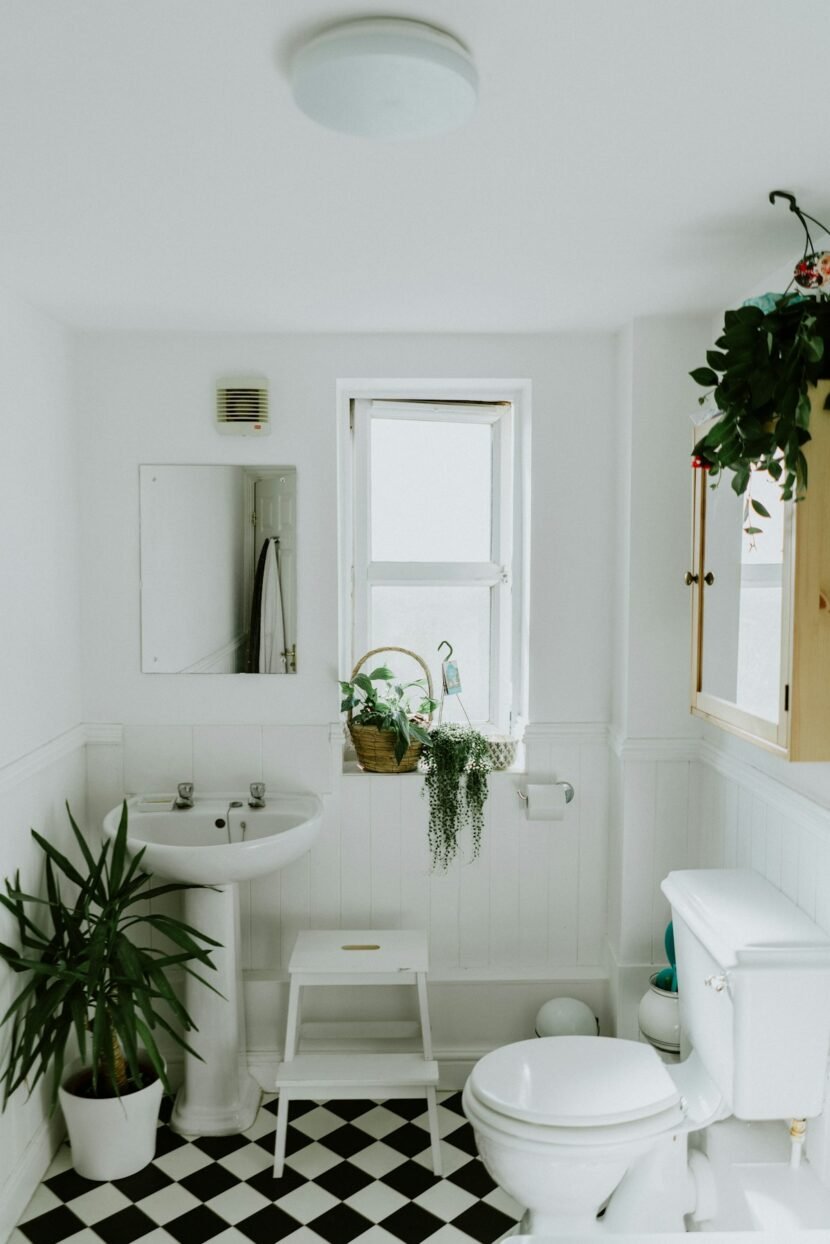 Organized small apartment bathroom with over-toilet shelf and wicker baskets