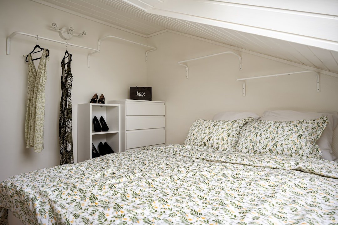 A neatly arranged small bedroom with a bed next to a white dresser maximizing space