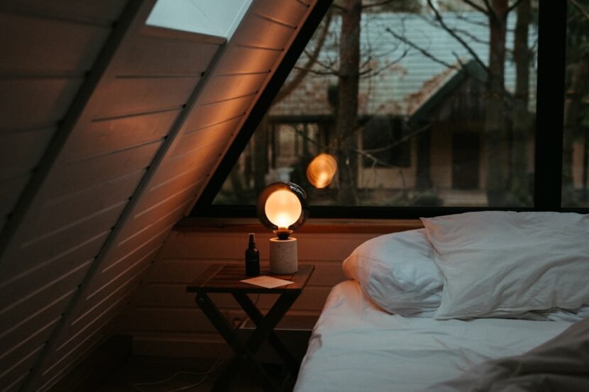 A cozy small bedroom lit with a warm bedside lamp creating a welcoming atmosphere