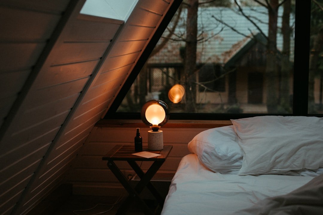 A cozy small bedroom lit with a warm bedside lamp creating a welcoming atmosphere