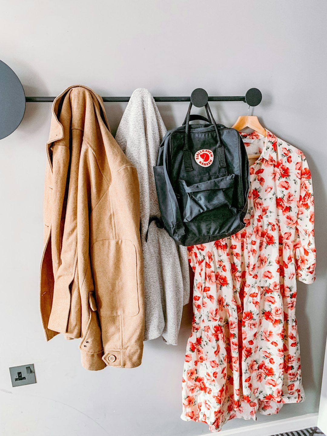 Wall hooks in a hallway with coats, a bag and a floral dress hanging neatly