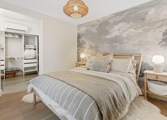 A renter-friendly bedroom decorated with clean white and gray bedding and damage-free decor