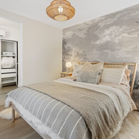 A renter-friendly bedroom decorated with clean white and gray bedding and damage-free decor