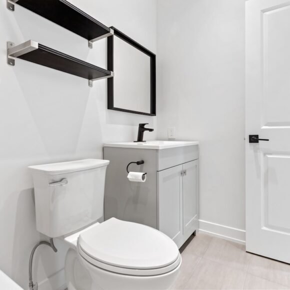 A small apartment bathroom with smart storage solutions including shelving above the toilet