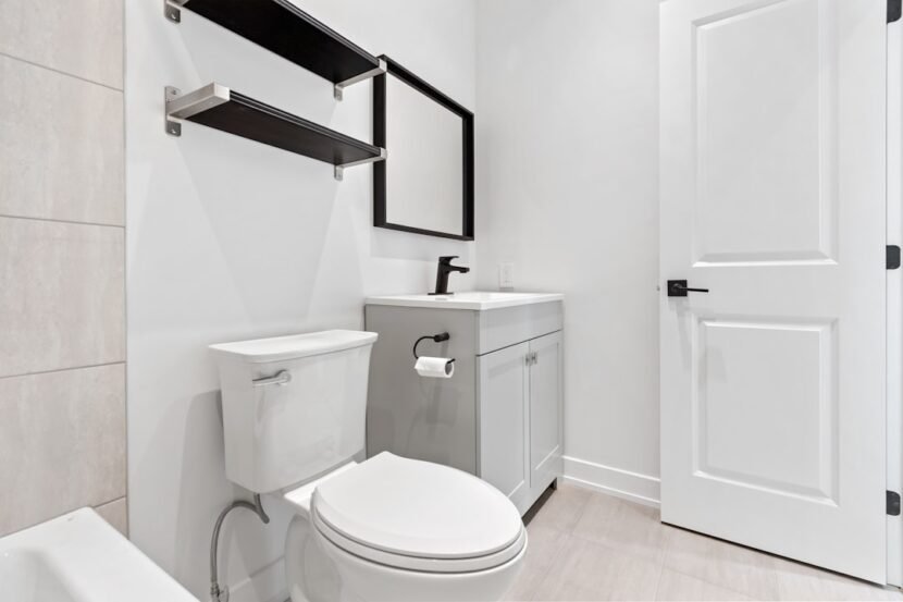 A small apartment bathroom with smart storage solutions including shelving above the toilet