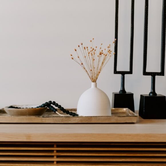 A stylish white ceramic vase styled next to decorative black table accents on a shelf, showing affordable home decor that looks custom