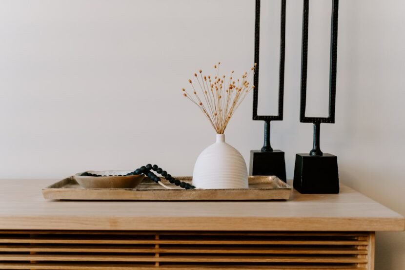 A stylish white ceramic vase styled next to decorative black table accents on a shelf, showing affordable home decor that looks custom