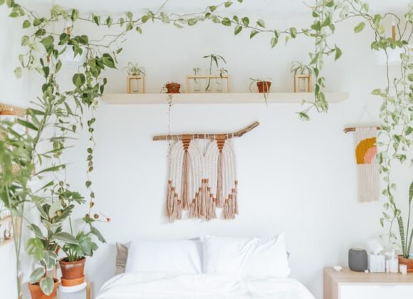 A dreamy boho bedroom with trailing houseplants draped above the bed, showing an airy uncluttered bohemian style