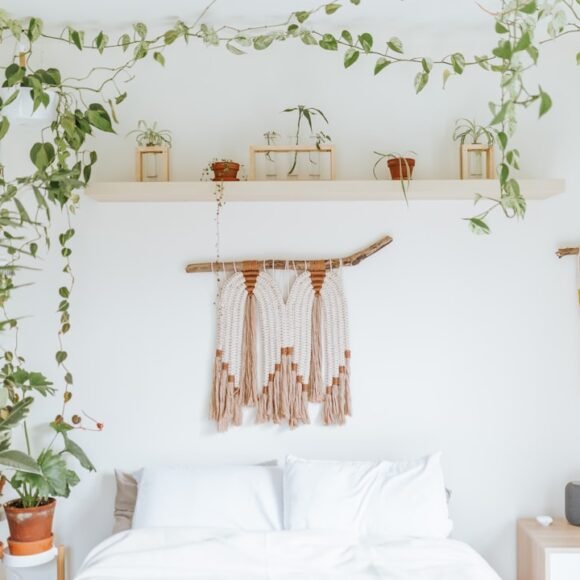 A dreamy boho bedroom with trailing houseplants draped above the bed, showing an airy uncluttered bohemian style