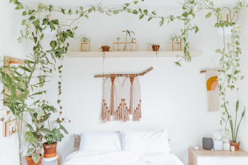 A dreamy boho bedroom with trailing houseplants draped above the bed, showing an airy uncluttered bohemian style