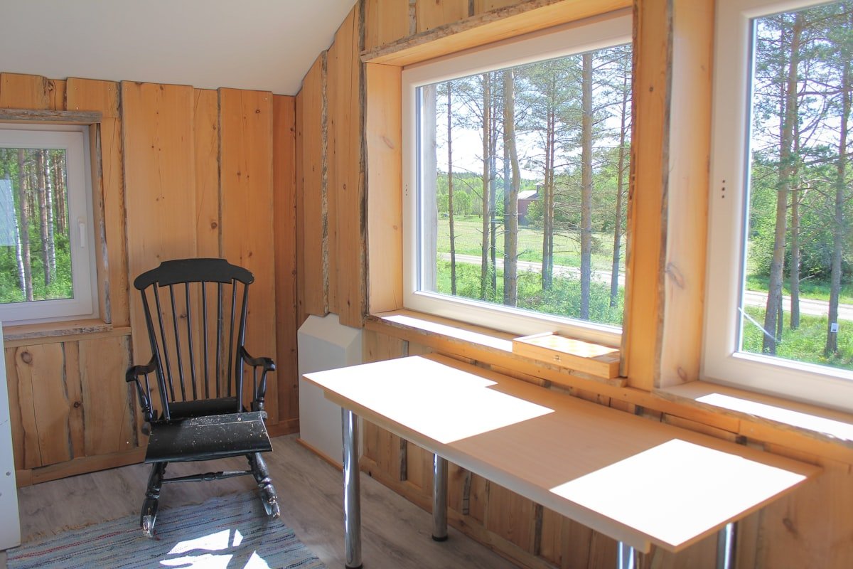 Wooden rocking chair beside a cottage window with soft daylight