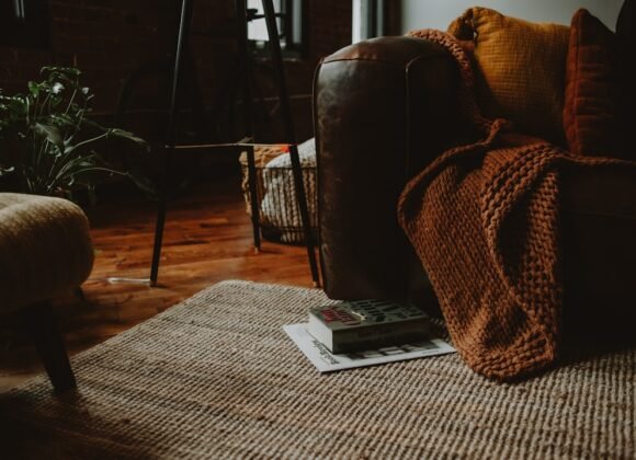 A cozy living room with a warm brown couch and armchair styled for autumn, showing fall apartment decor ideas