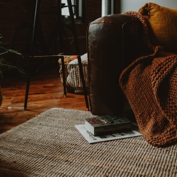 A cozy living room with a warm brown couch and armchair styled for autumn, showing fall apartment decor ideas