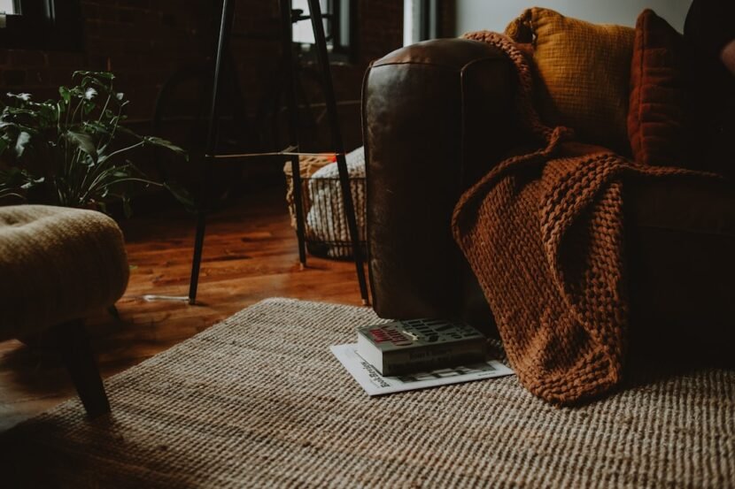 A cozy living room with a warm brown couch and armchair styled for autumn, showing fall apartment decor ideas