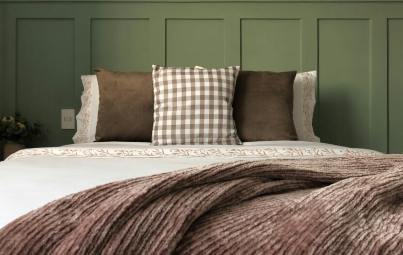 Bed layered with a folded knit blanket and mixed cushions