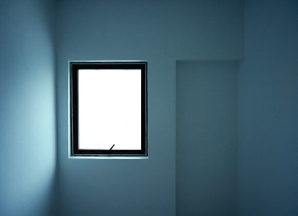 Minimalist room painted in a soft grey blue with a bright window