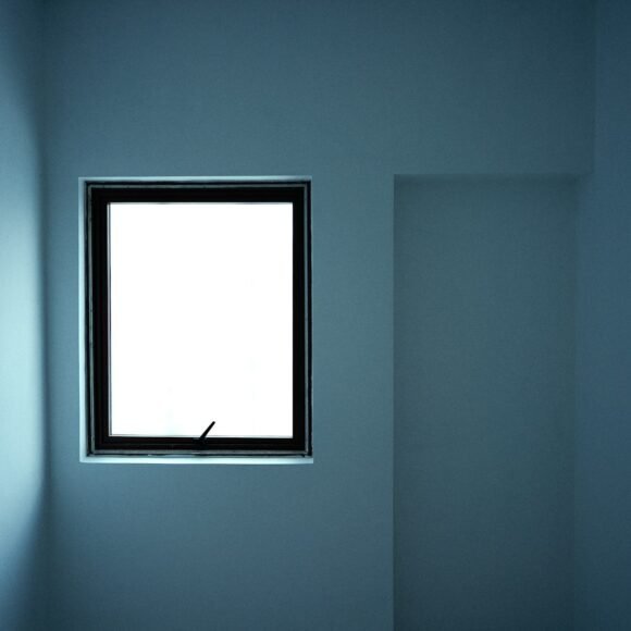 French Blue Paint Colors Taking Over Living Rooms in 2026 Minimalist room painted in a soft grey blue with a bright window