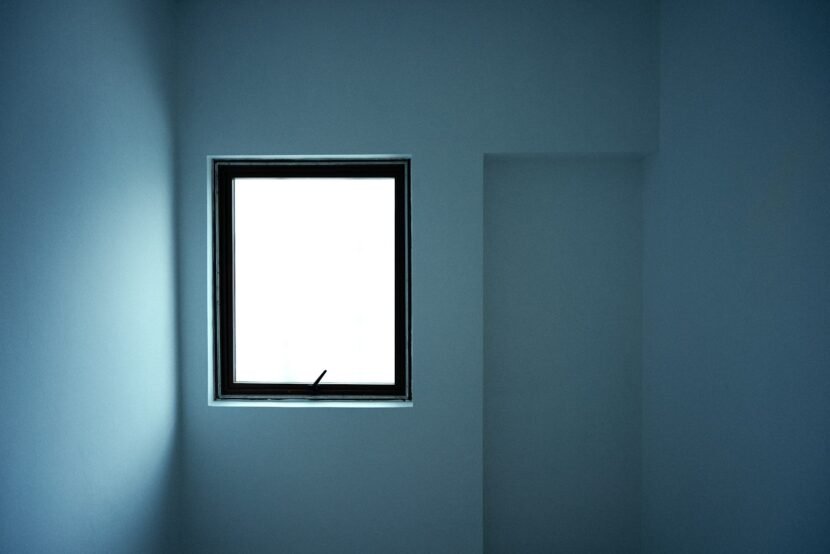 Minimalist room painted in a soft grey blue with a bright window