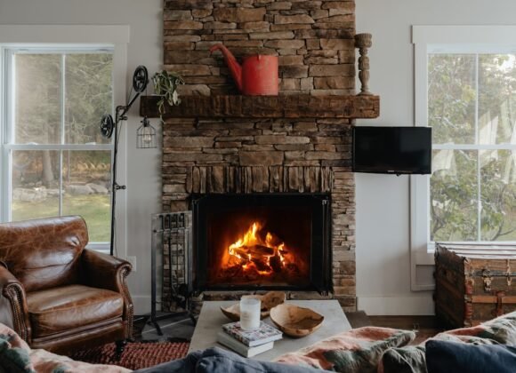 A cozy living room with a lit fireplace, soft warm lighting, and layered textiles perfect for fall and winter evenings