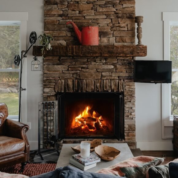 A cozy living room with a lit fireplace, soft warm lighting, and layered textiles perfect for fall and winter evenings