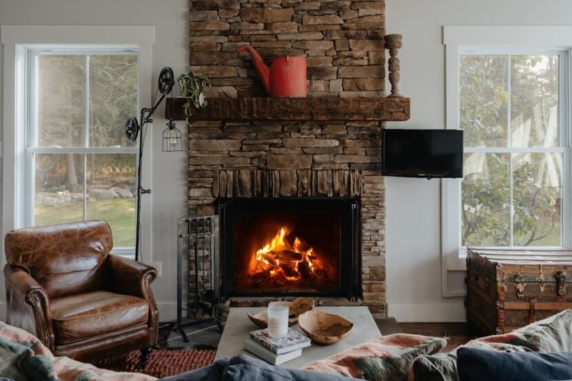A cozy living room with a lit fireplace, soft warm lighting, and layered textiles perfect for fall and winter evenings