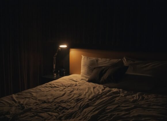 Cozy small bedroom with no natural light lit by a warm bedside lamp