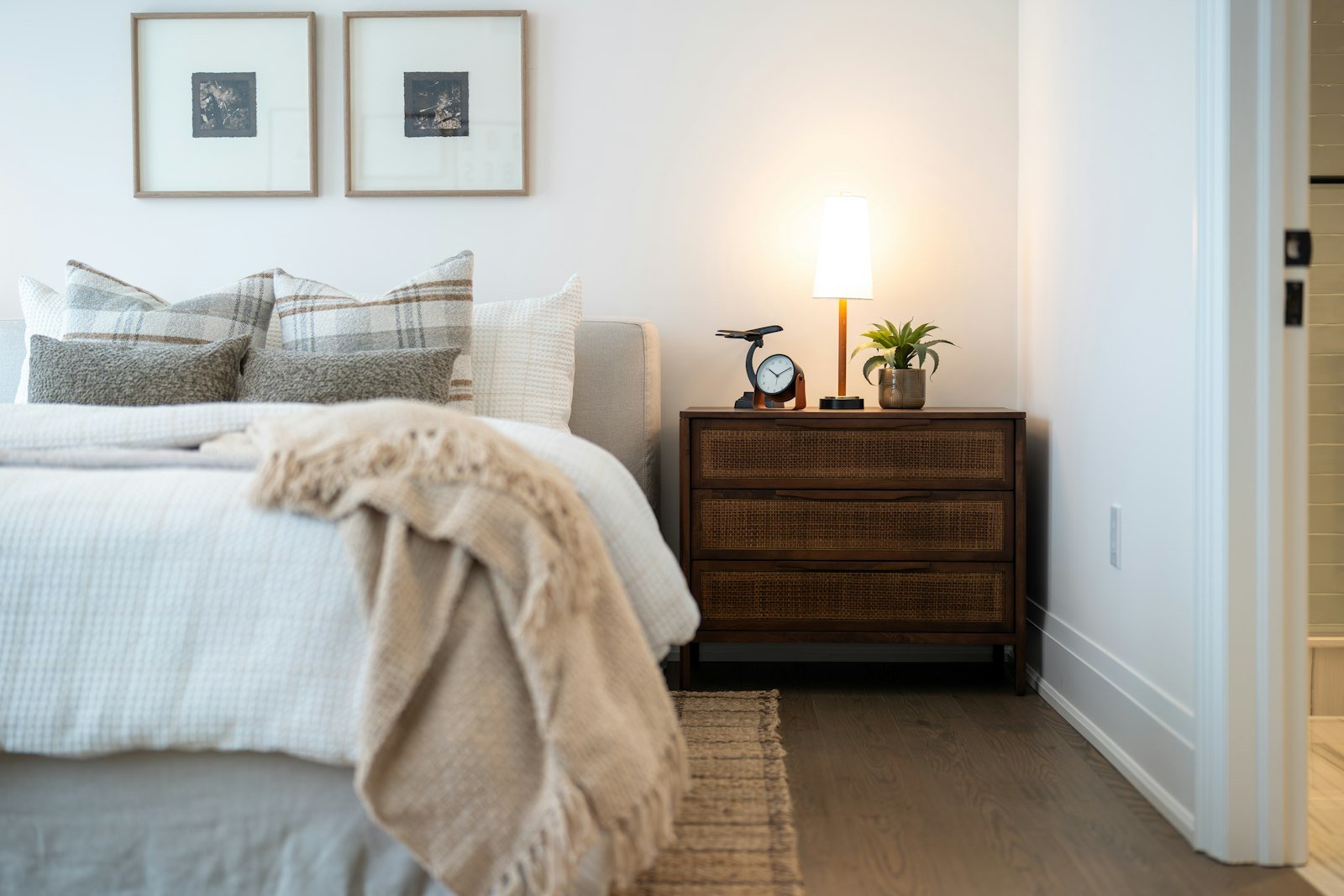Bedside lamp casting warm low light in a pared back minimalist bedroom