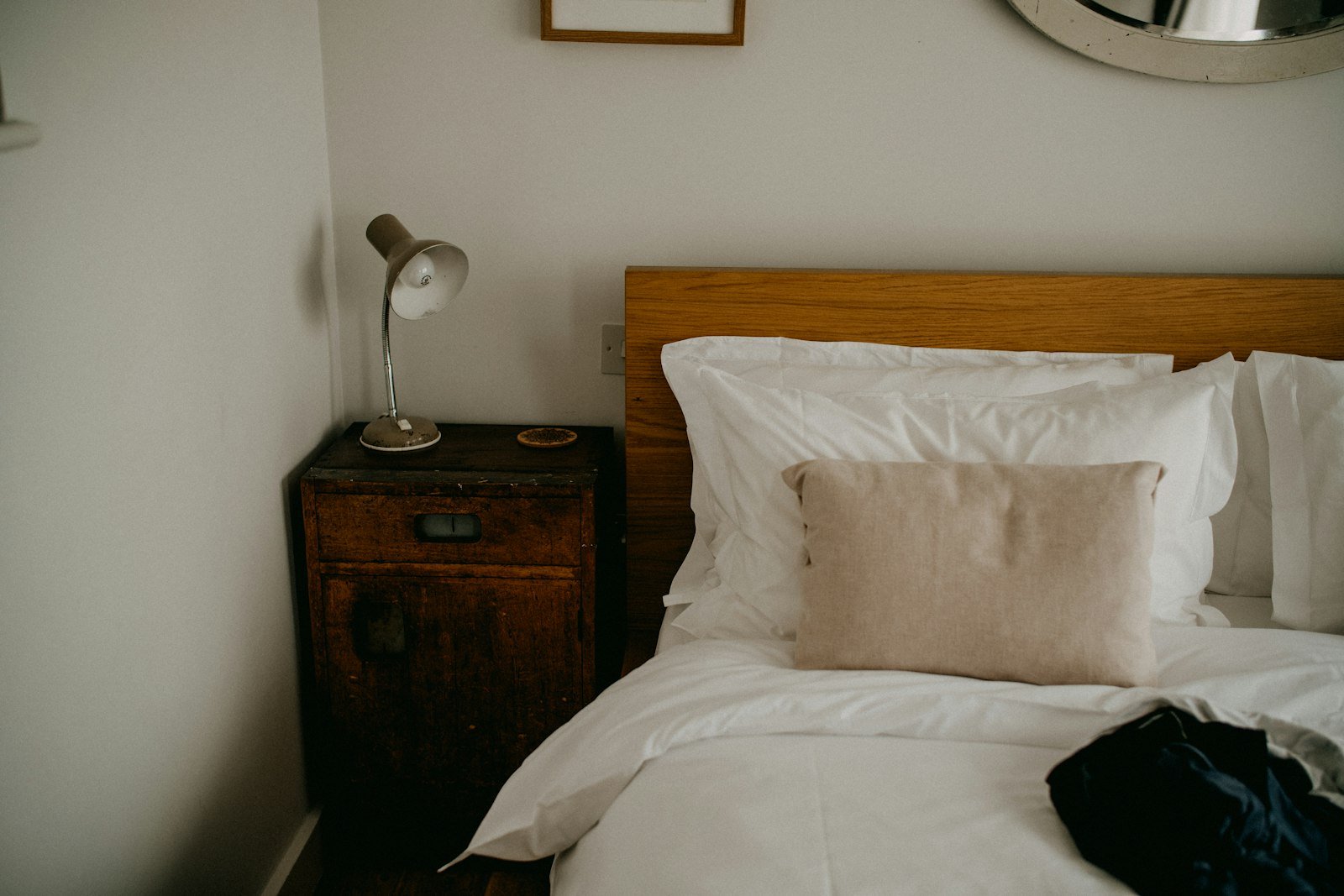 Minimalist bedroom with a made bed, wooden bedside table and warm neutral walls